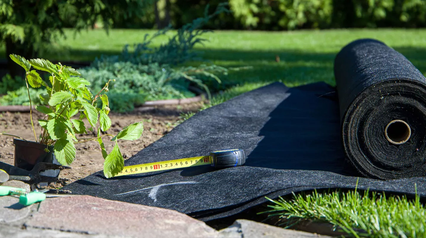 Vue en plongée d'un emplacement circulaire dans un jardin résidentiel, montrant des couches de gravier et de sable disposées pour accueillir une piscine